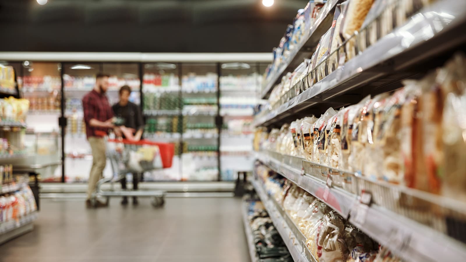 Concentrated young loving couple in supermarket choosing products.