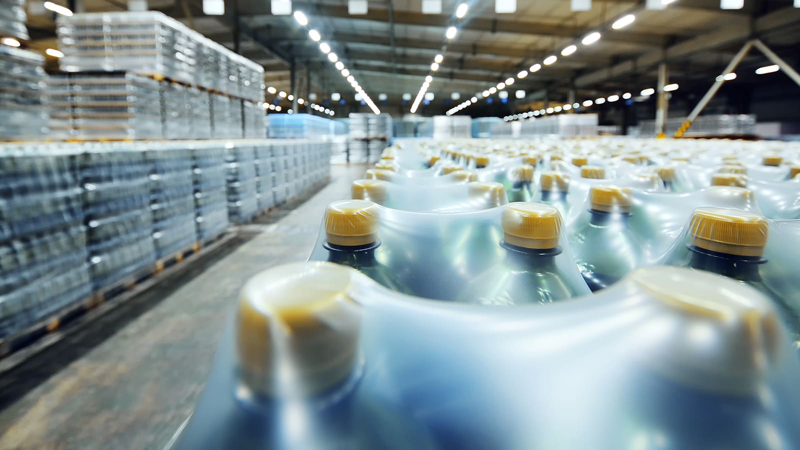 a huge industrial warehouse with plastic food wrap wrapped plastic bottles with carbonated drinks,  water or beer.