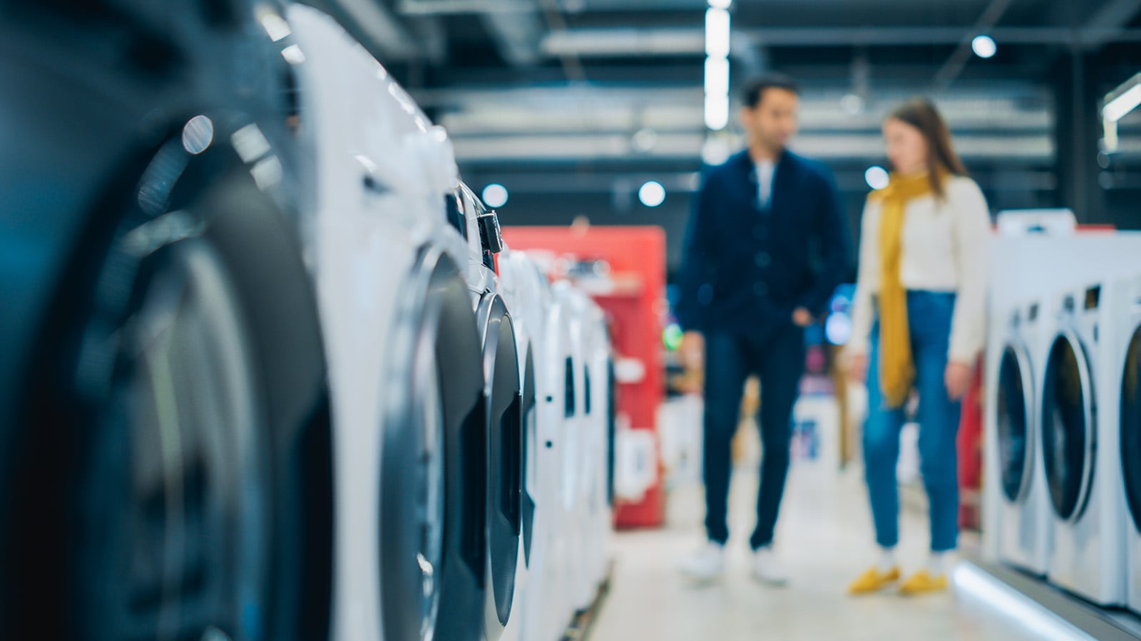 Multicultural Couple Evaluates Washing Machine Choices at Home Electronics Store. Man and Woman in Search of a Reliable Laundry Appliance. Customers Explore Modern Laundry Solutions in a Retail Shop